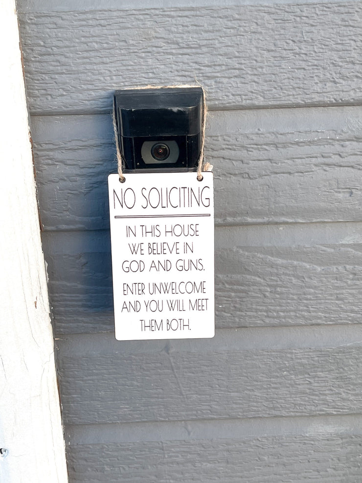 No soliciting / In this house we believe in God and guns. Enter unwelcome and you will meet them both / Protective hanging doorbell sign
