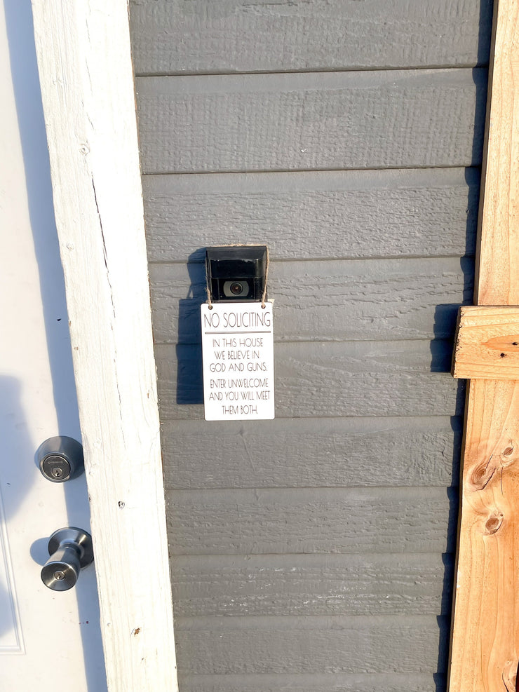 No soliciting / In this house we believe in God and guns. Enter unwelcome and you will meet them both / Protective hanging doorbell sign