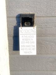 No soliciting / In this house we believe in God and guns. Enter unwelcome and you will meet them both / Protective hanging doorbell sign