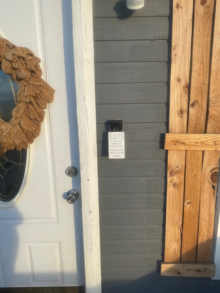 No soliciting / In this house we believe in God and guns. Enter unwelcome and you will meet them both / Protective hanging doorbell sign